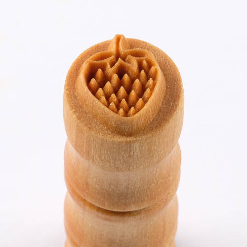 Detail of a ceramic texture roller carved with a strawberry design, ideal for creating unique surface patterns in clay.