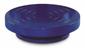 Blue ceramic trimming wheel with concentric rings, used for shaping and refining pottery in the ceramics studio.