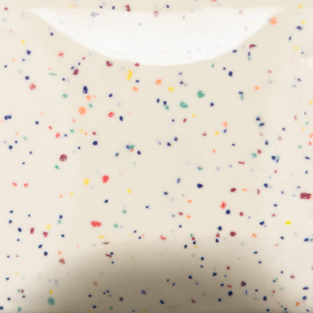 Colorful speckled clay body showing red, blue, yellow, and green flecks on a white background, ideal for ceramic projects.