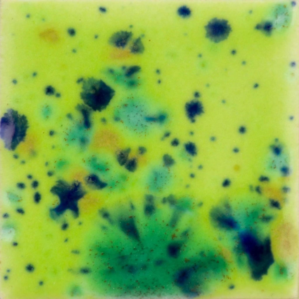 Textured ceramic tile featuring vibrant splashes of yellow, green, and blue glazes, showcasing decorative glazing techniques.
