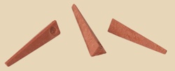 Three triangular clay wedges in red clay, used for shaping and constructing pottery or ceramics in a studio setting.
