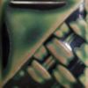 Close-up of a ceramic piece featuring a smooth green glaze with textured patterns, ideal for pottery and sculpting projects.