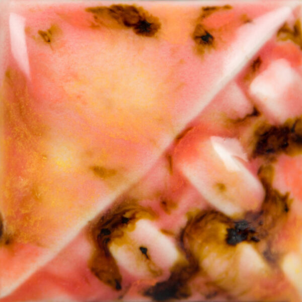 Close-up of a ceramic glaze sample featuring pink, cream, and brown hues, showcasing varied surface textures and effects.