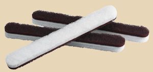 Four ceramic finishing sponges, featuring a white abrasive side and a black sponge side, used for smoothing pottery surfaces.