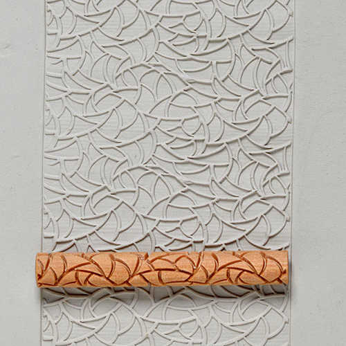Textured clay slab featuring an intricate leaf pattern, with a decorative roller on the bottom, ideal for pottery decoration.