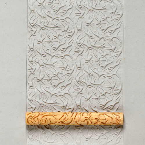 Embossed clay slab decorated with intricate leaf patterns using a textured rolling pin, ideal for pottery and sculpture projects.