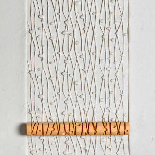 Impression of textured clay with a decorative roller showcasing elegant leaf patterns, ideal for pottery decoration.