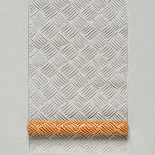 Textured clay impression made with a carved rolling pin on white clay, showcasing decorative patterns for pottery designs.
