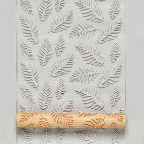 Clay slab with leaf patterns impressed by a texture roller, ideal for pottery decoration and sculptural projects.