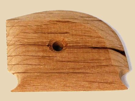 Wooden rib tool for shaping and smoothing clay in pottery, featuring a rounded edge and central hole for grip.