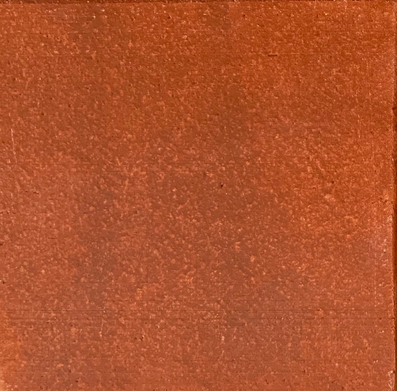 Close-up of a textured terracotta clay tile, showcasing rich reddish-brown color ideal for pottery and sculpture.