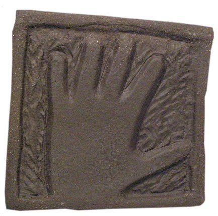 Hand-shaped clay impression in a rectangular mold, showcasing texture for ceramic casting or sculpture projects.