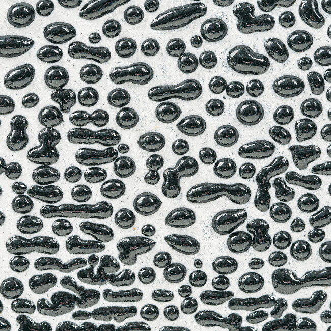 Glossy black and clear glaze pooling on white clay, showcasing unique textures in ceramic surface decoration techniques.