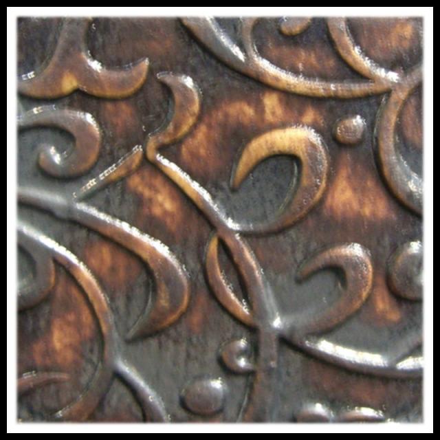 Intricate brown and black ceramic relief pattern showcasing decorative scrolls and curves, ideal for pottery embellishment.