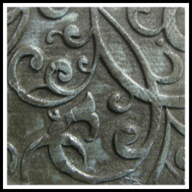 Textured ceramic surface with intricate swirling patterns, glazed in a dark, lustrous color reminiscent of stoneware.
