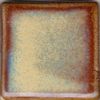 A square ceramic tile showcases a layered glaze with a gradient of yellow, blue, and reddish-brown hues.