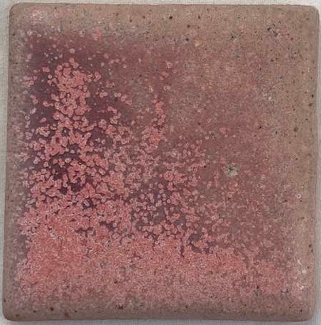 A square ceramic tile with a mottled pink and brown glaze, showcasing texture and firing effects typical of stoneware.