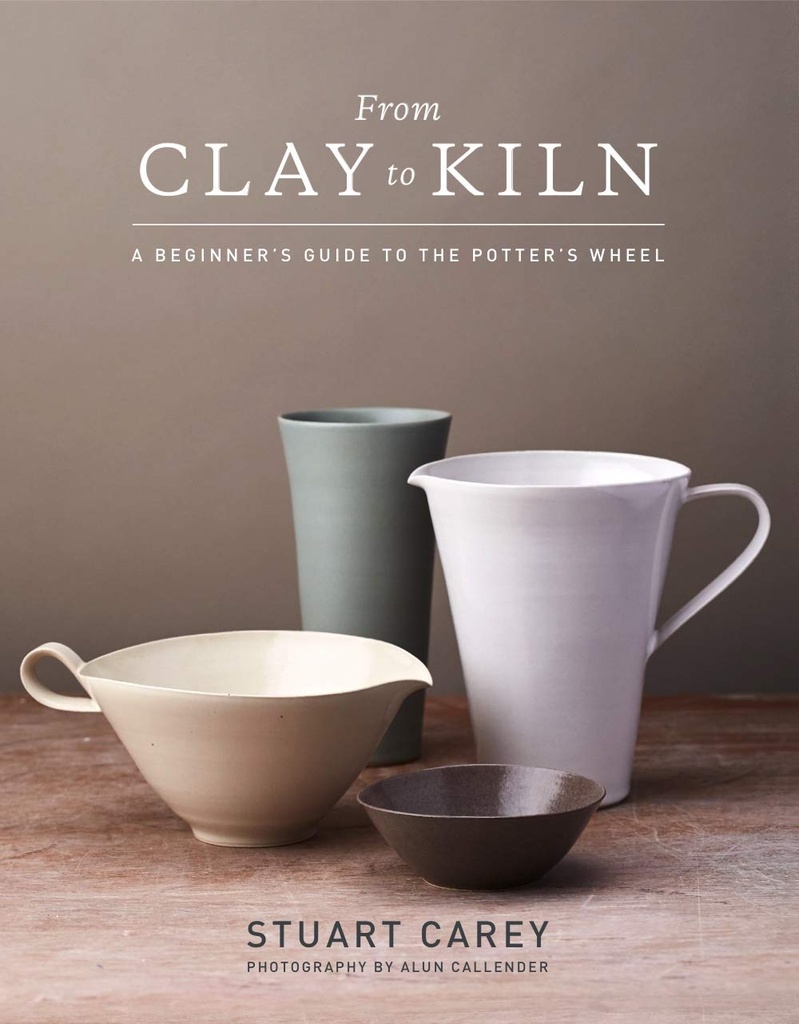 Four ceramic vessels in varied glazes: a white pitcher, a green cup, and two bowls in cream and dark brown, on a wooden surface.