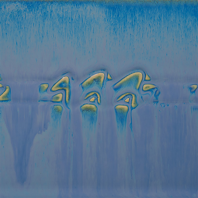 Blue and yellow blended glaze surface with fluid patterns, showcasing ceramic glazing technique for decorative pottery.