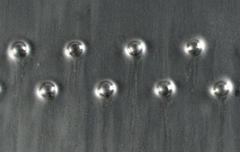 Close-up of a textured ceramic surface featuring glossy silver spheres on a dark glazed background, ideal for decorative pottery.