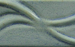 Textured ceramic tile with a wavy design in a soft blue glaze, showcasing clay finish and decoration techniques.
