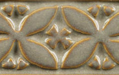 Close-up of a ceramic tile featuring a textured floral design in gray and amber glaze from Georgies Ceramic & Clay Company.