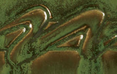 Close-up of a glossy green ceramic glaze with intricate raised patterns, showcasing texture and depth for pottery decoration.