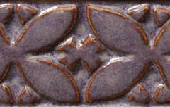 Close-up of a textured ceramic tile featuring a floral design in a deep purple glaze with brown highlights.