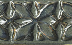 Close-up of a textured ceramic tile in rich metallic glaze, featuring a floral design; ideal for decorative pottery projects.