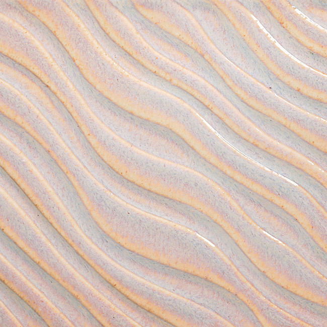 Close-up of a wavy ceramic surface with a glossy, pale blue glaze showcasing subtle purple flecks.