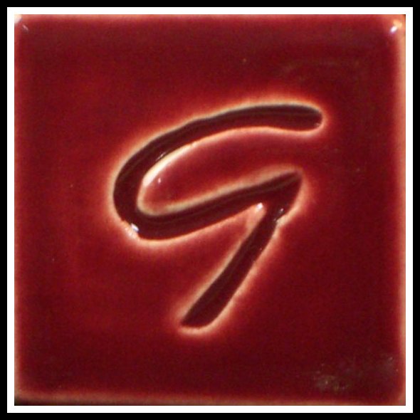 Glossy red pottery glaze tile featuring an embossed letter G, ideal for ceramic decoration and studio projects.