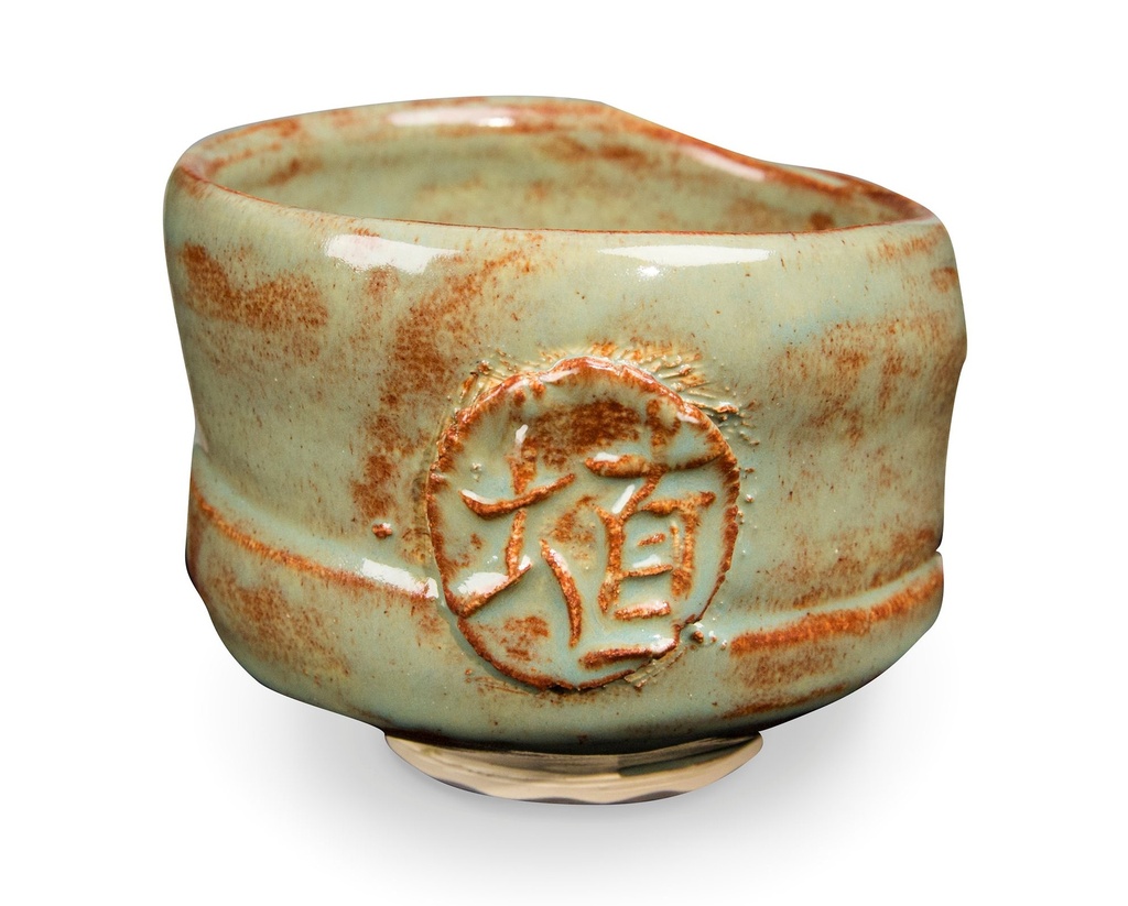 Ceramic bowl with a textured green glaze and carved design, showcasing pottery techniques and firing detail.