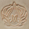 Intricate clay imprint of a stylized letter M surrounded by leaf motifs, showcasing detailed ceramic decoration techniques.