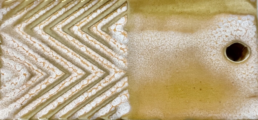 Textured ceramic tile showcasing a zigzag pattern in earthy tones with a hole, ideal for decoration or sculptural use.