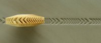 Carving tool creating a zigzag texture on soft clay surface in a pottery studio, showcasing ceramic decoration techniques.