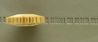 A ceramic trimming tool rests on a gray surface, displaying its serrated edge for creating texture in clay.