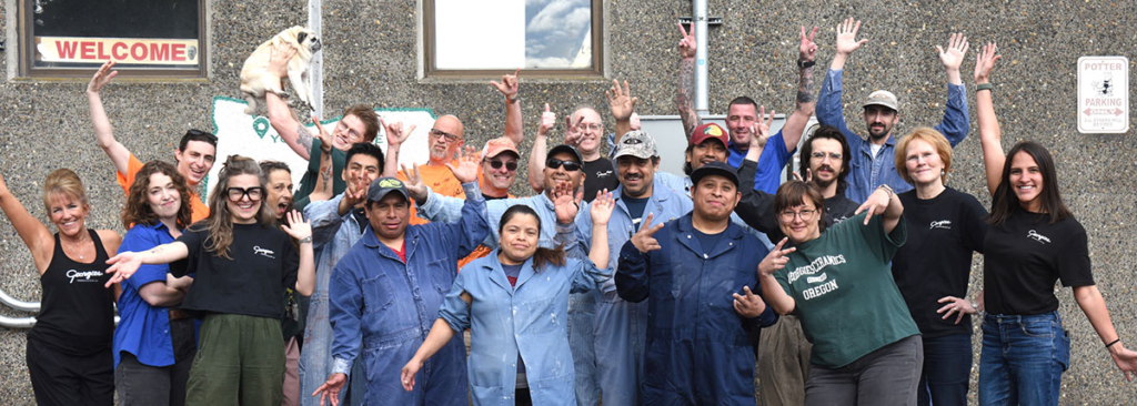 A diverse group of ceramic artists and staff from Georgie's Ceramic & Clay Company joyfully posing outside their studio.