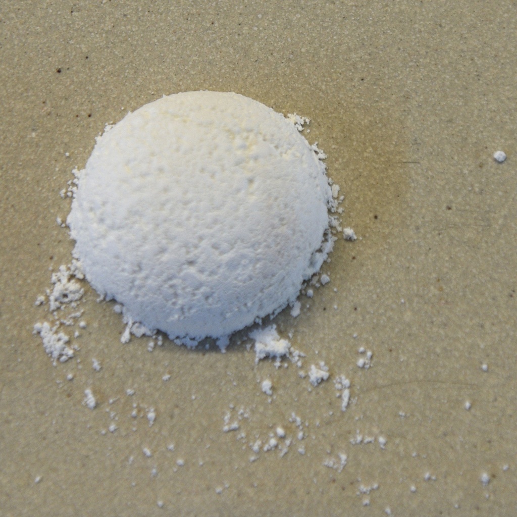 White ceramic glaze powder in a small mound on a textured surface, ready for mixing and application in pottery.