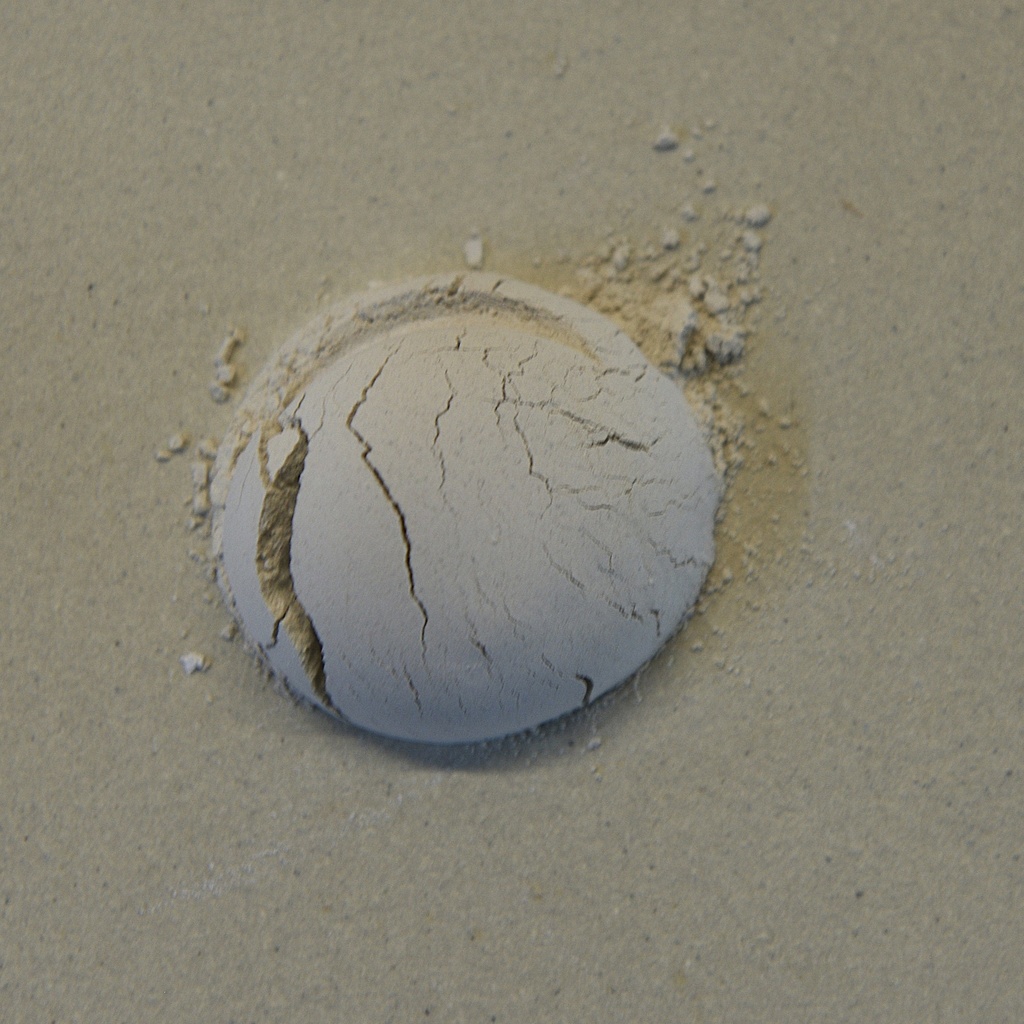Cracked ball of dry clay rests on a light-colored surface, showcasing potential for ceramic sculpture or pottery.